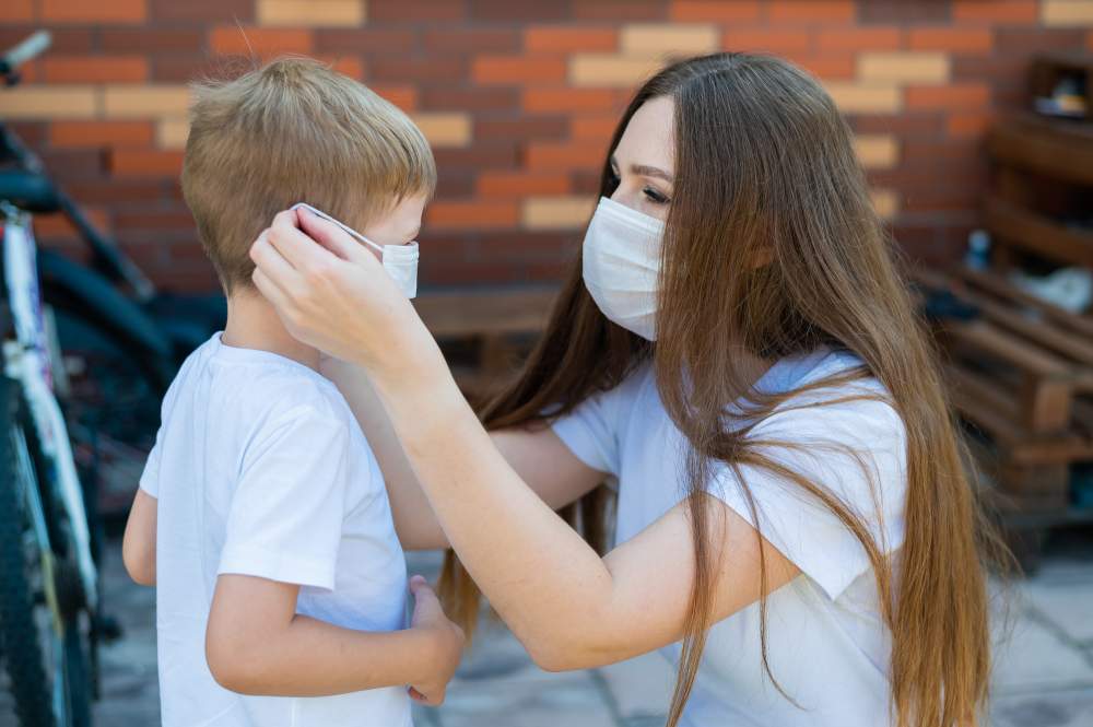 Woman helping young boy get his mask on